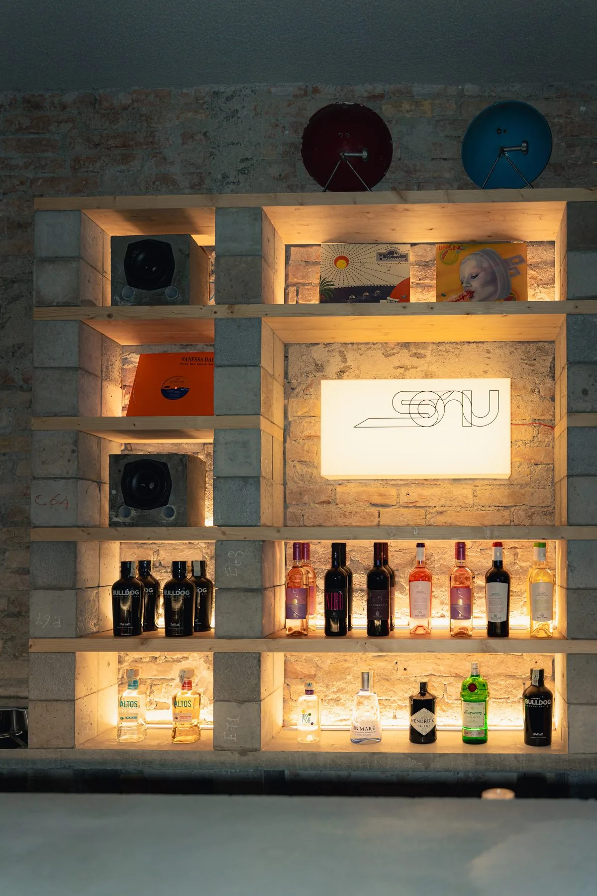 La bottigliera di SONU con insegna luminosa, gin, vini calabresi e diffusori in cemento