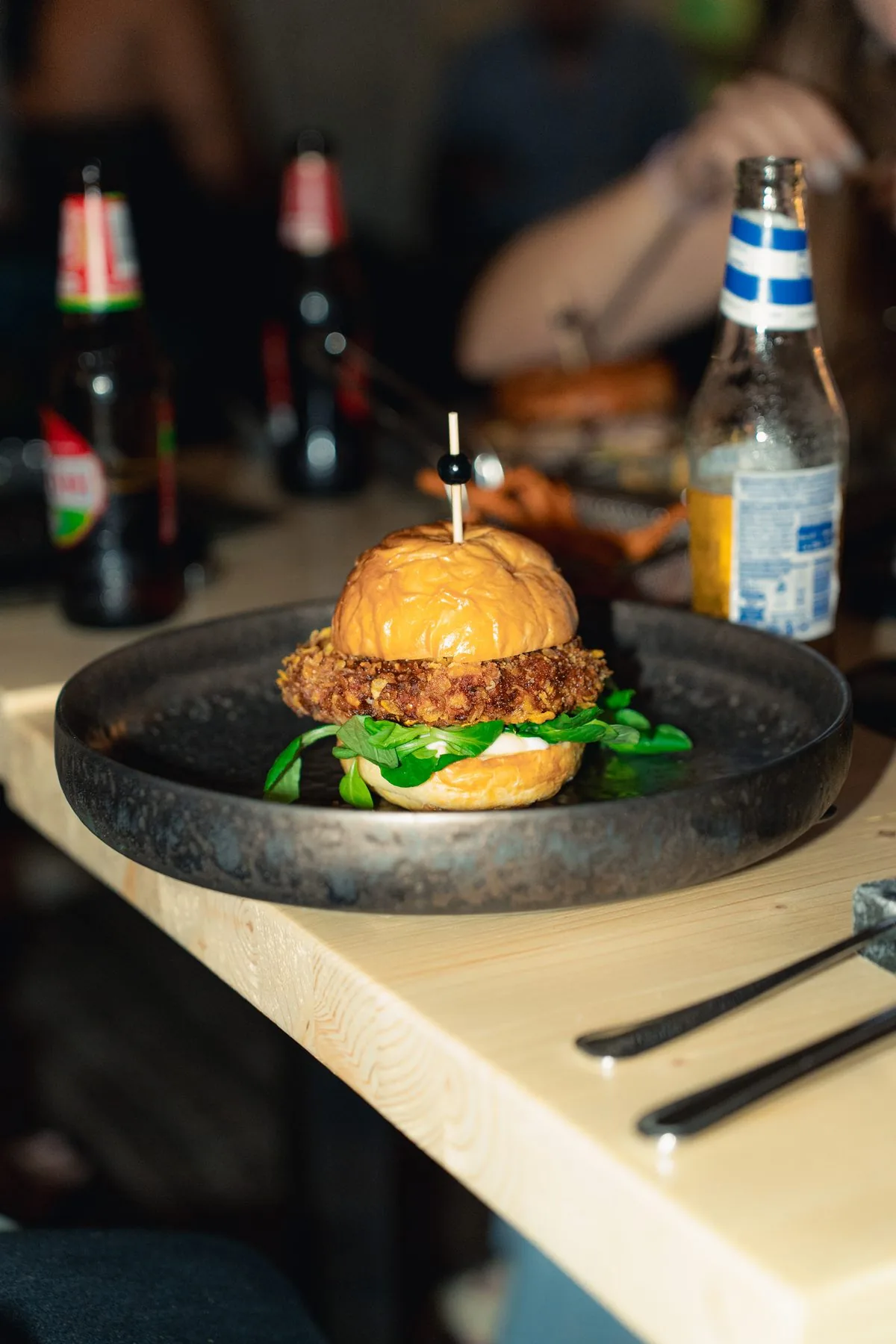 Burger con pollo croccante e valerianella su piatto nero